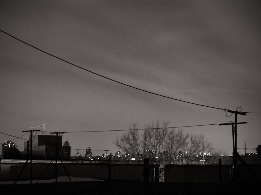 City skyline at night with a telephone wire in the foreground