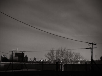 City skyline at night with a telephone wire in the foreground