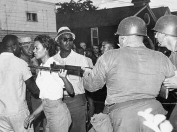 The activist Gloria Richardson walking past National Guardsmen during a civil rights march in Cambridge