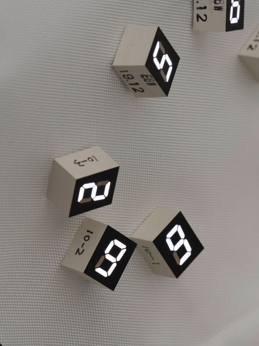 A scattering of digital blocks depicting the numbers two, nine, nine, and five in an art installation by Tatsuo Miyajima