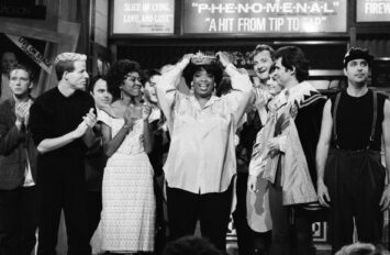 Oprah Winfrey wears a tiara, standing with cast members of SNL