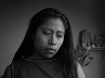 A woman looks down mournfully in a still from the film Roma.