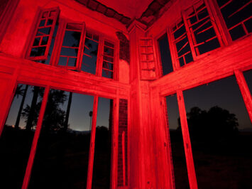 Corner of a windowed room with walls lit up red at night. Thomas Hawk / Creative Commons