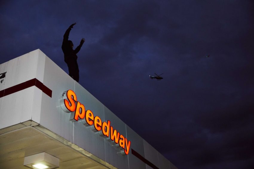 Silhouette of a man standing atop a Speedway gas station at night