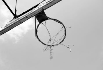 Black and white photograph of a basketball hoop shot upwards from below