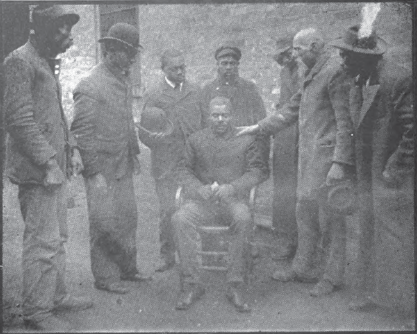 Woman in a white dress stands outside of a gate where a man is inside.